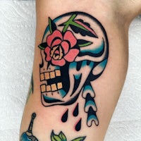 a tattoo of a skull with a flower on it